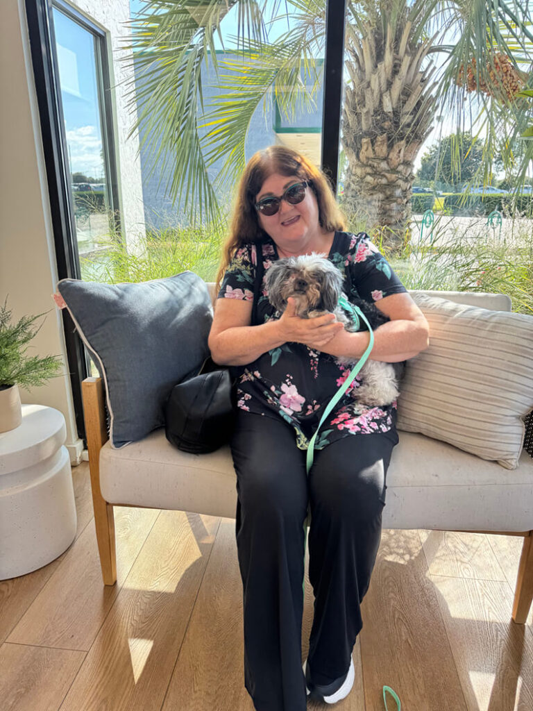 One lady holding a small gray and white dog.