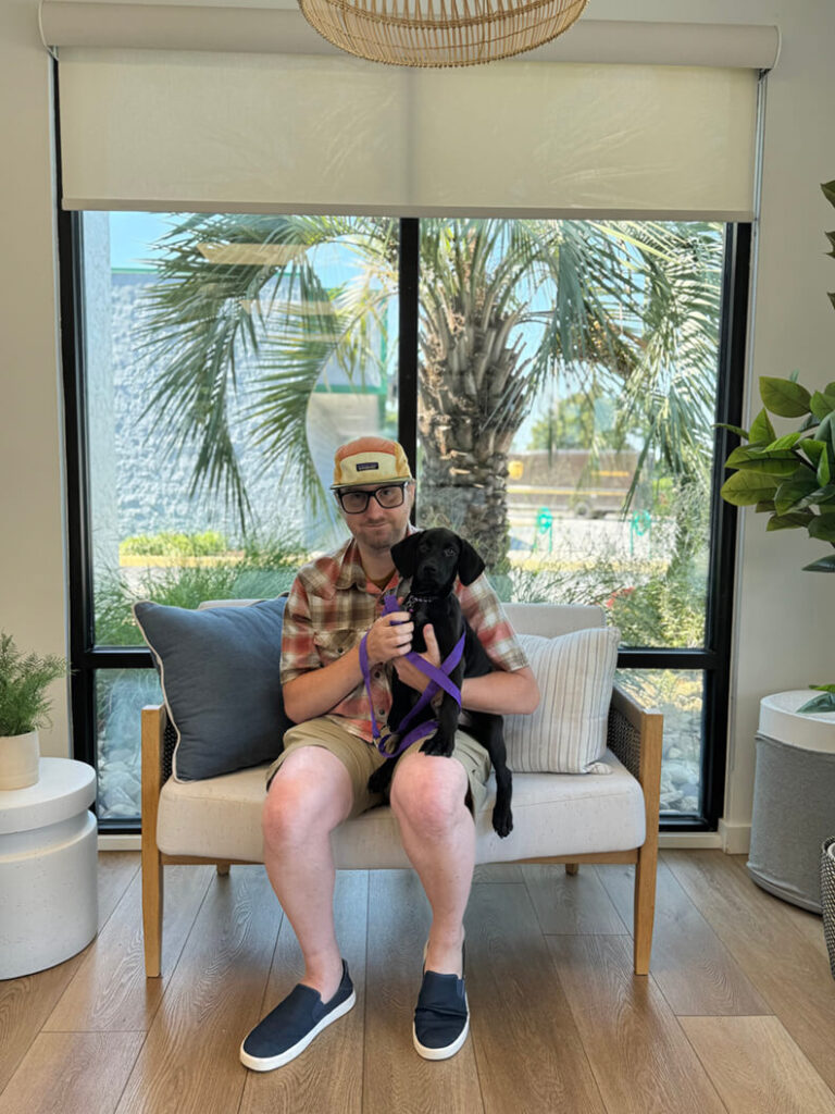 One person in a plaid shirt and hat, holding a black puppy called Dopey.