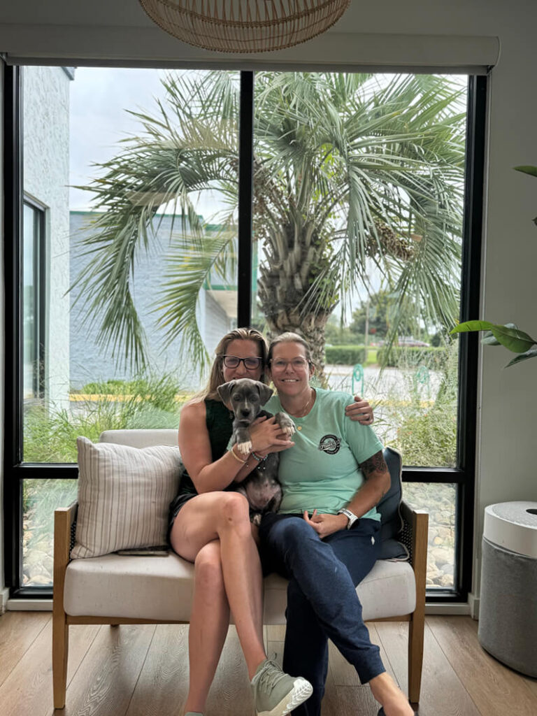 Family of 2 holding a gray puppy called Eeyore.
