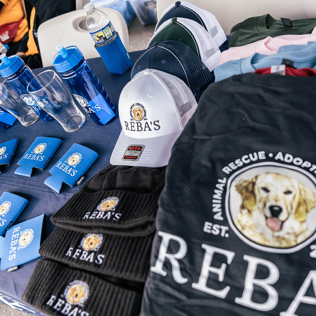 Reba's merch examples - koozies, cups, hats, beanies, and shirts