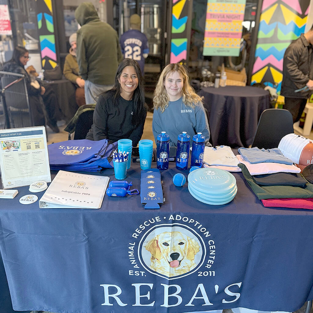 Staff members sitting at the Reba's merch table at the Puppy Bowl