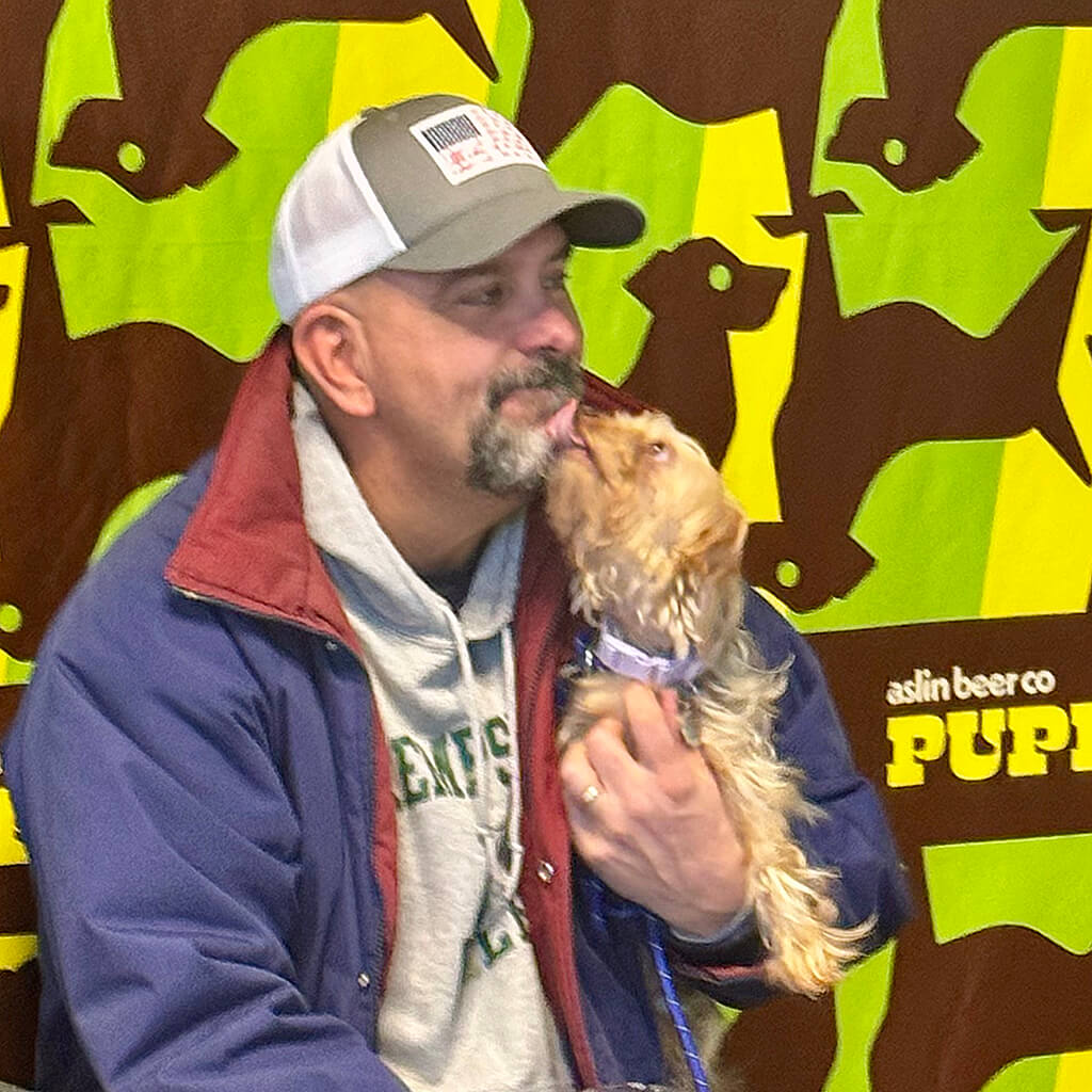 The little brown dog gives kisses to a man at the Puppy Bowl