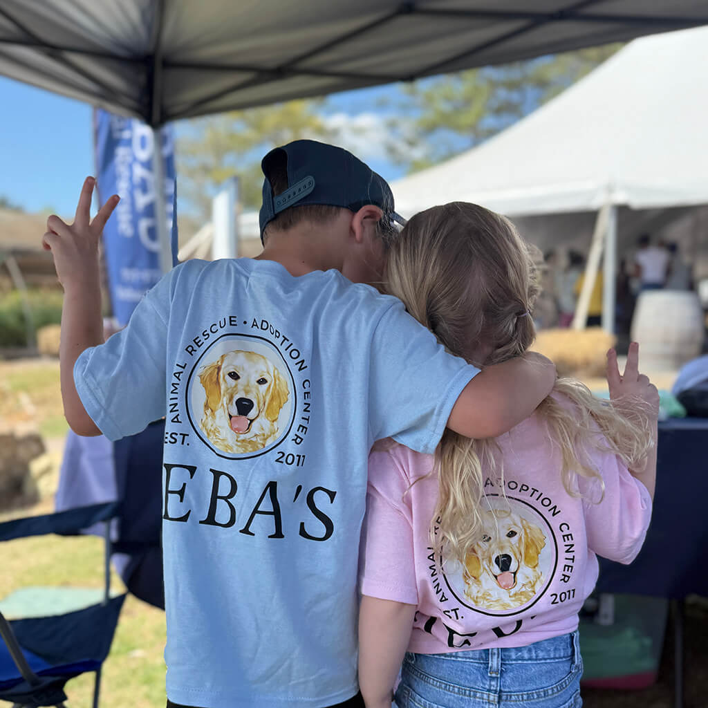 A boy hugs a girl and they both give peace signs wearing Reba's t-shirts
