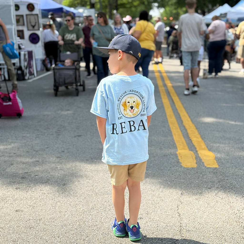 young boy standing in the street wearing a Reba's t-shirt