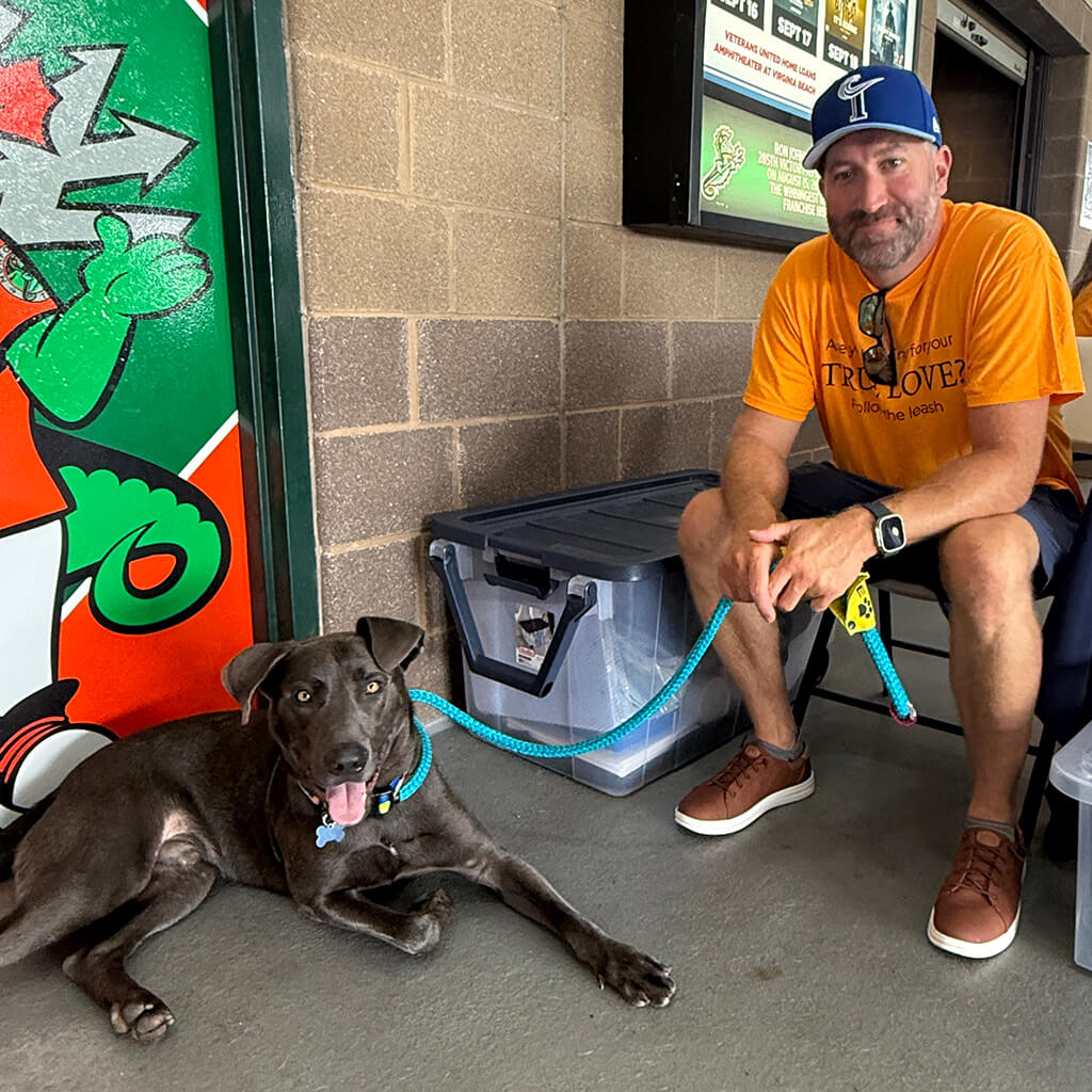 A volunteer sits with one of our adoptable dogs